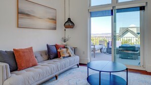 Una sala de estar moderna con un sofá, una mesa redonda y un amplio ventanal con vistas al exterior.