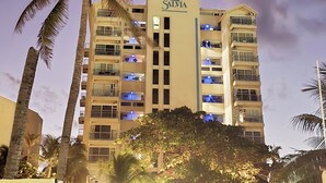 A multi-story hotel with balconies and a palm tree in front. - Beach & Nightlife Paradise; Top floor and ocean view (Cancún)