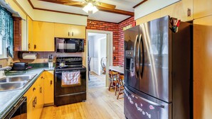 A kitchen with wooden cabinets, stainless steel appliances, and a brick wall. - 9 Mi to Lake George Village: Home in Queensbury (Queensbury)