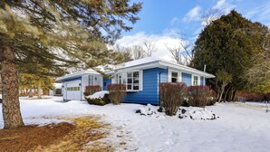 A single-story house with a blue exterior, surrounded by snow-covered ground and trees. - 9 Mi to Lake George Village: Home in Queensbury (Queensbury)