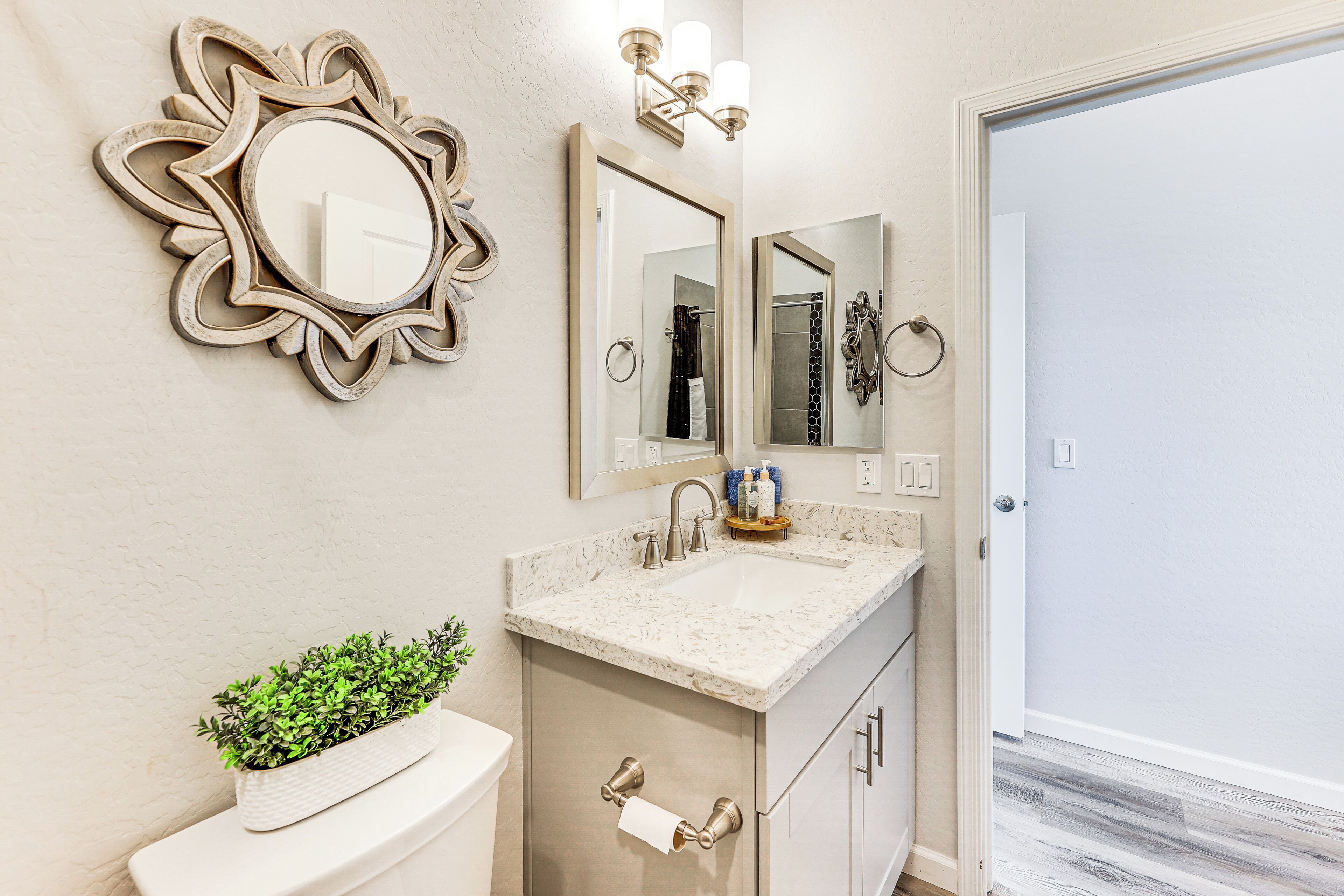 Une salle de bain avec un lavabo en marbre, des toilettes, un miroir et un élément décoratif mural.