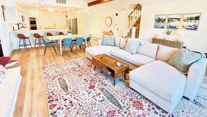 A modern living room with a white sofa, blue chairs, a wooden coffee table, and a patterned rug.