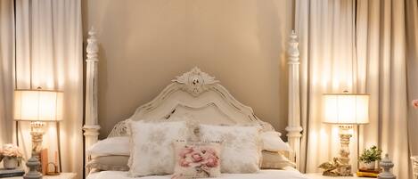 A bedroom with a large bed, ornate headboard, and a chandelier.