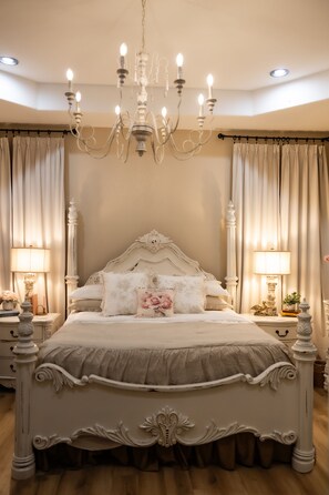 A bedroom with a large bed, ornate headboard, and a chandelier. - Charming Farmhouse, Hot Tub, Pool, Outdoor Kitchen, Farm animals & Stocked Pond. (Diana)