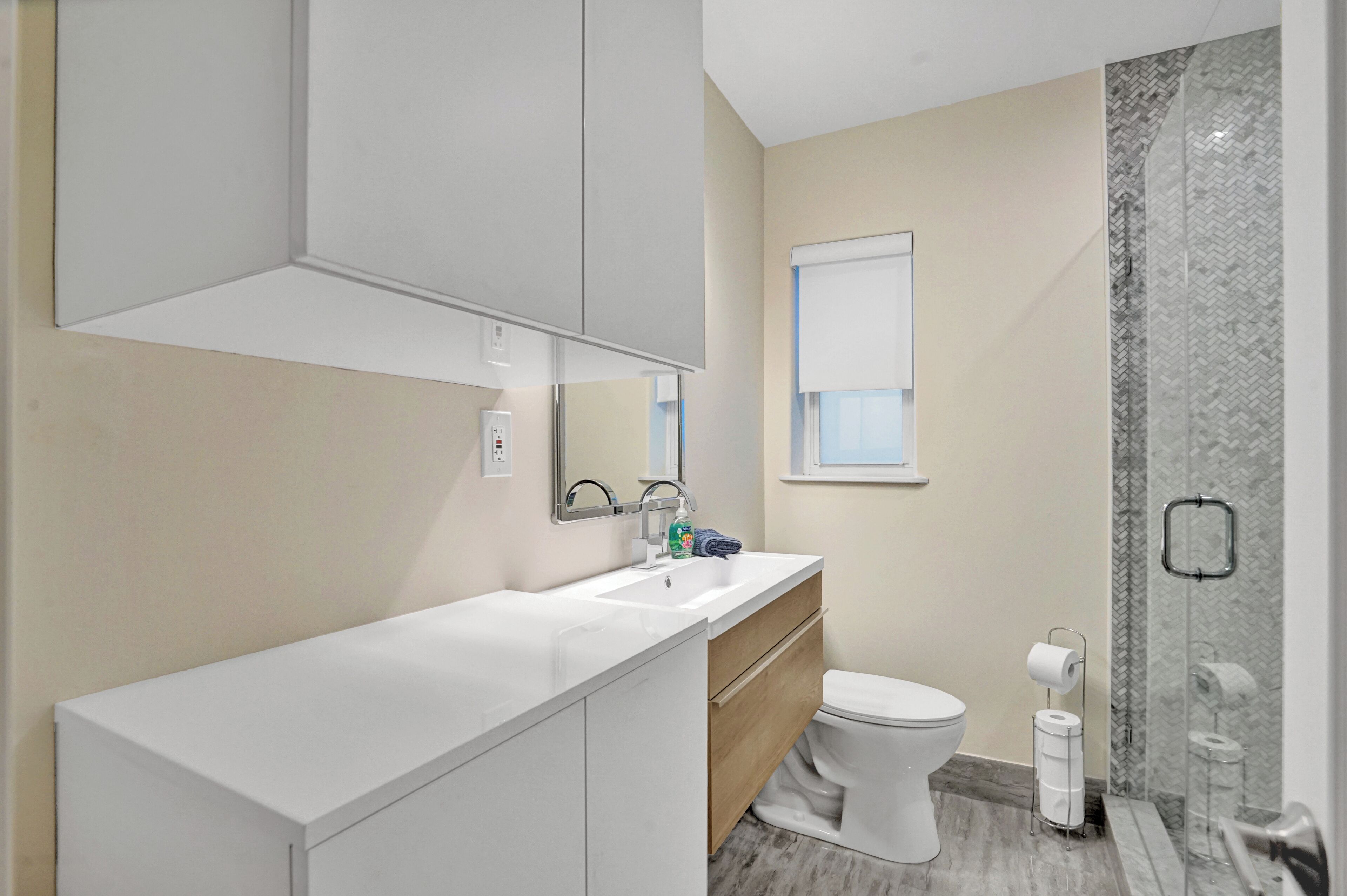 A modern bathroom with a white vanity, a toilet, and a shower area with a glass door.