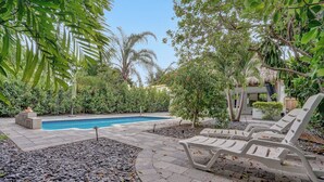 A pool area with lounge chairs, a stone pathway, and lush greenery. - Daddy House (Fort Lauderdale)