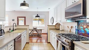 A modern kitchen with white cabinets, a large stove, and a dining area with a wooden table.