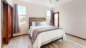 A bedroom with a wooden bed, a ceiling fan, and a window with curtains.