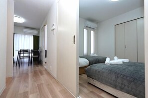 Una habitación de hotel con cama, armario, escritorio con sillas y ventana con cortinas.