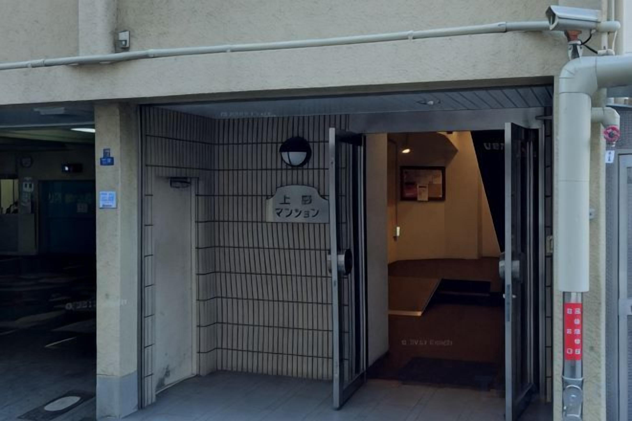 A hotel entrance with a metal gate, a sign above the gate, and a staircase leading inside.