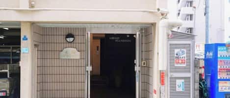 A hotel entrance with a sign indicating 'URINO MANSION' and a security camera above the door.