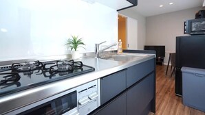 Une cuisine moderne équipée d’une cuisinière à gaz, d’appareils électroménagers en acier inoxydable, d’un évier et d’une plante en pot.