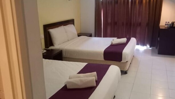 A hotel room with two beds, a desk, and a window with curtains. - Syajie Koptown Hotel (Segamat)