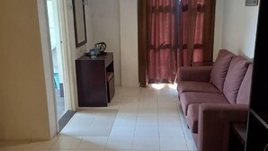 A living room with a sofa, a small table, and a TV. - Syajie Koptown Hotel (Segamat)