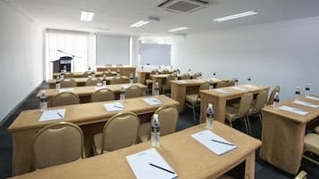 A conference room with multiple tables, chairs, and presentation screens.