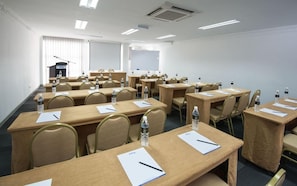 A conference room with multiple tables, chairs, and presentation screens.