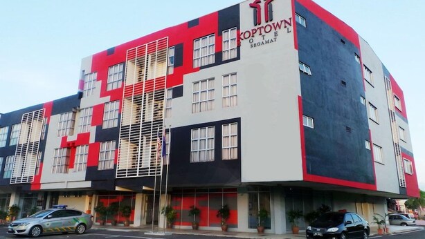 A multi-story hotel with a distinctive red and black facade, featuring a prominent logo and signage. - Syajie Koptown Hotel (Segamat)