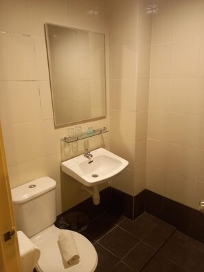 A small bathroom with a toilet, sink, and mirror. - Syajie Koptown Hotel (Segamat)
