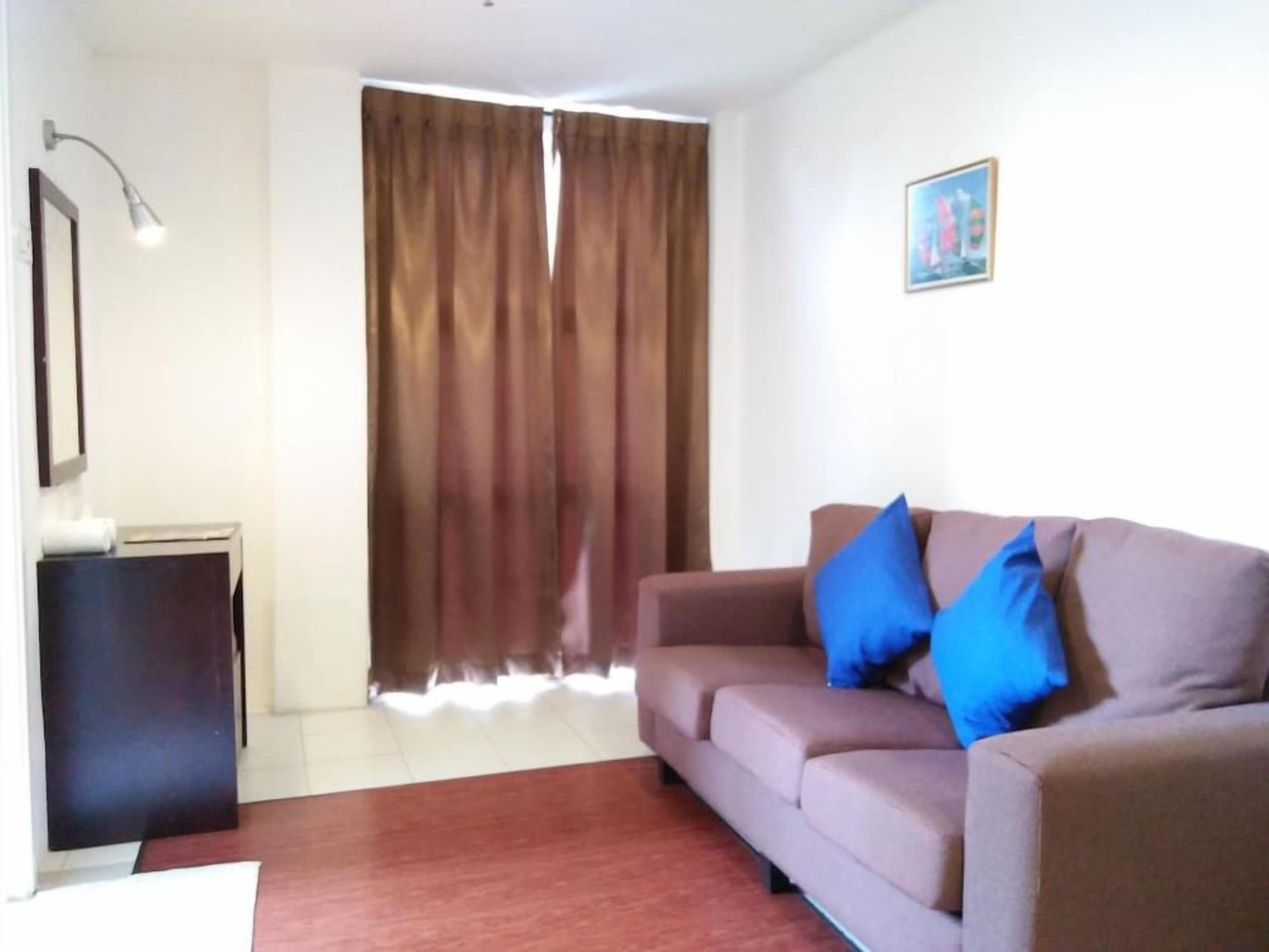 A living room with a sofa, a lamp, a picture on the wall, and a window with curtains.