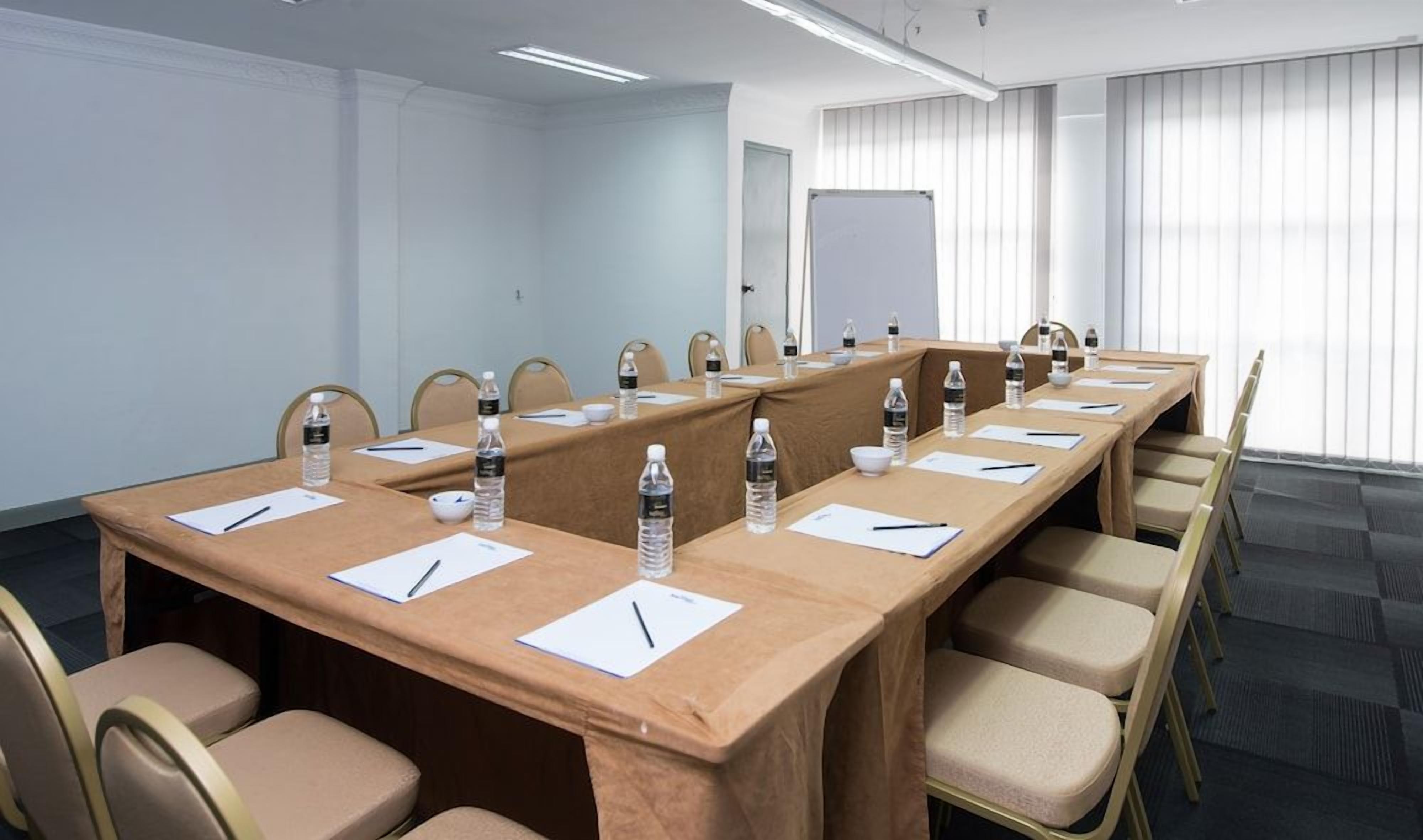 Uma sala de conferências com uma mesa comprida, cadeiras, garrafas de água e papéis.