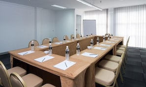 A conference room with a long table, chairs, water bottles, and papers.