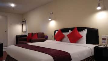 A hotel room with a large bed, two bedside lamps, a nightstand, and a chair.