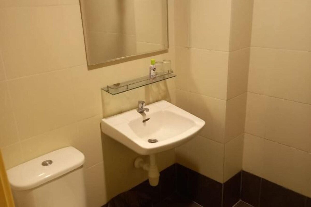 A bathroom with a white sink, a mirror above it, and a small shelf with toiletries.