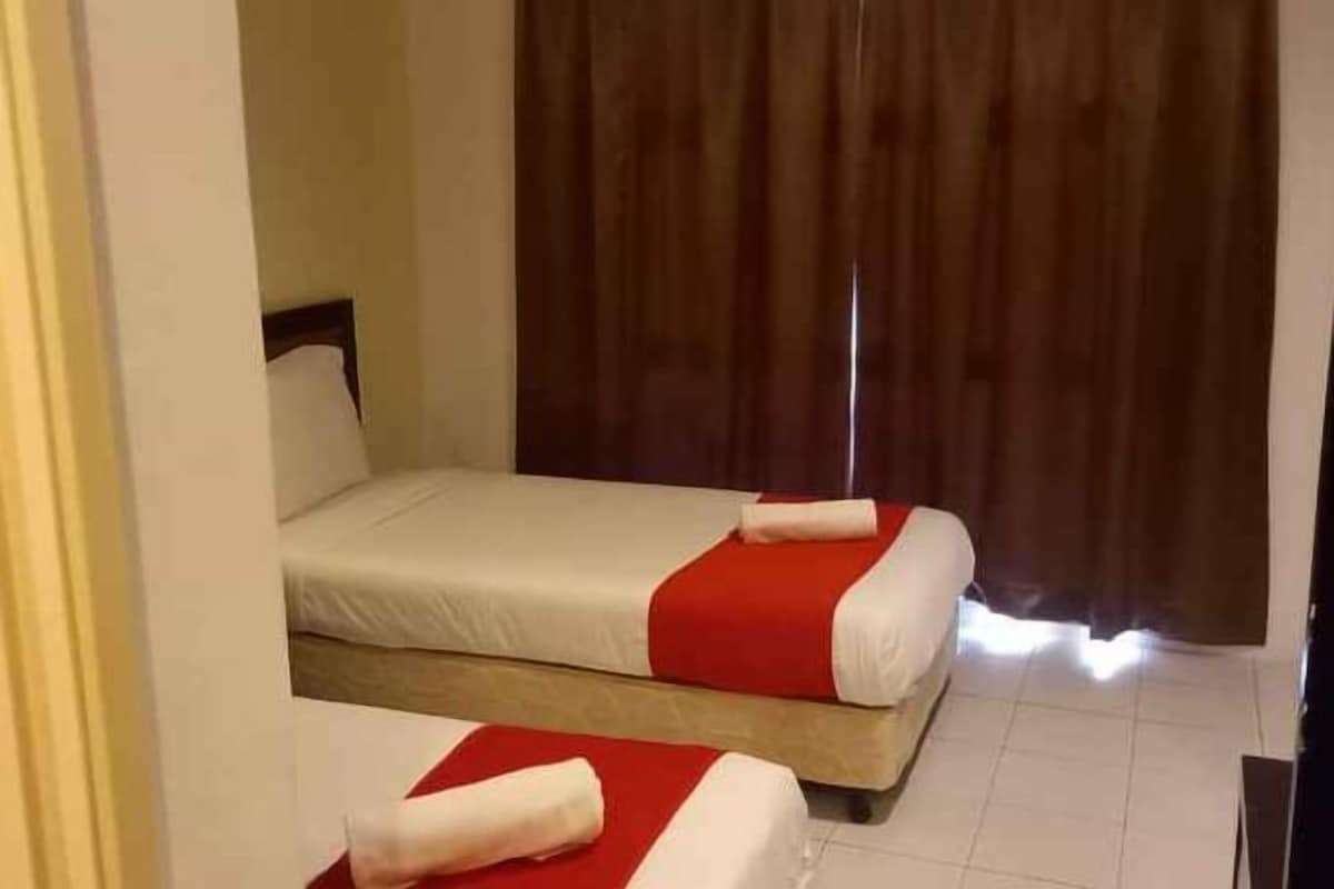 A hotel room with two beds, a wooden headboard, and a curtain.