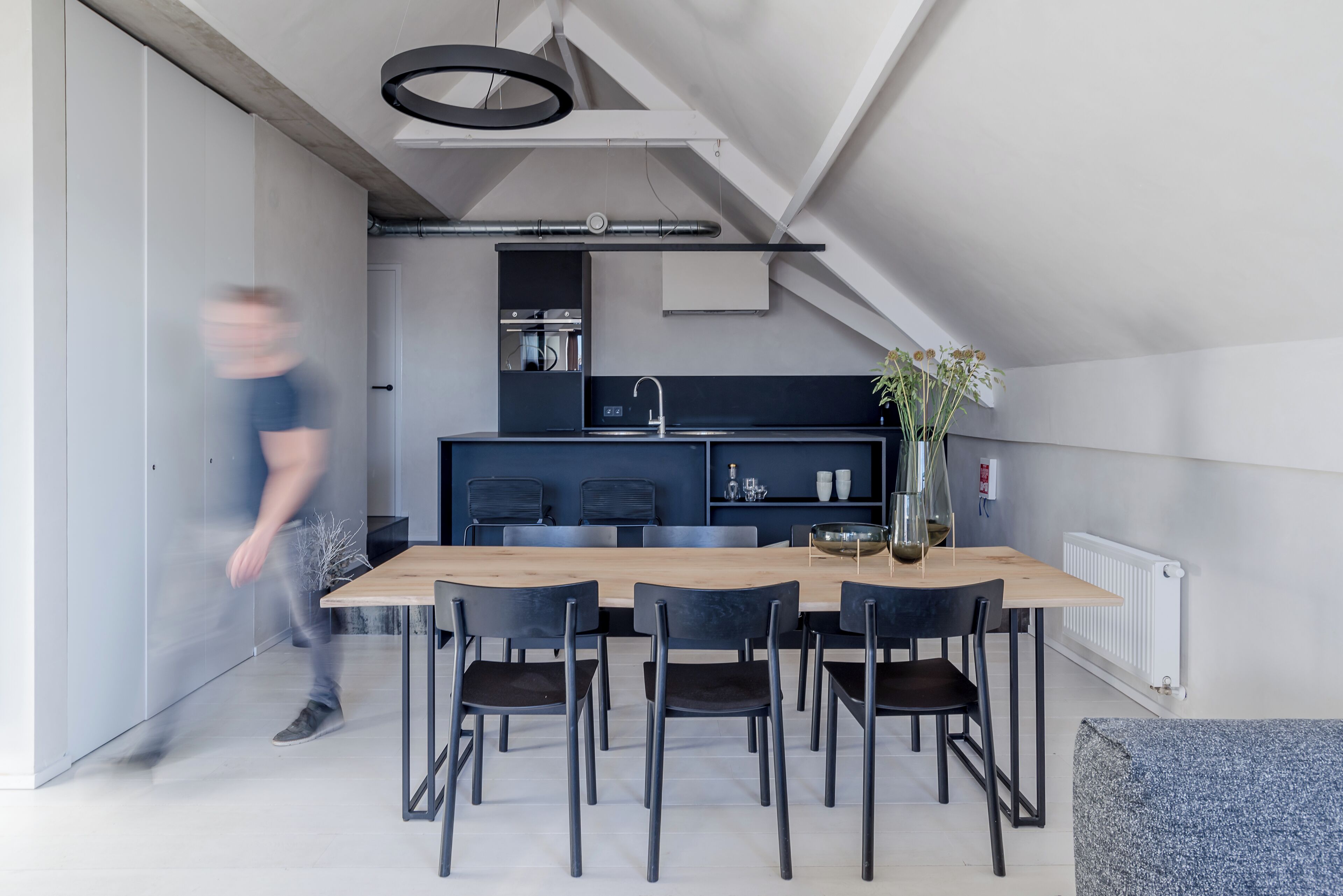 A modern kitchen with a central island, black chairs, and a dining table.
