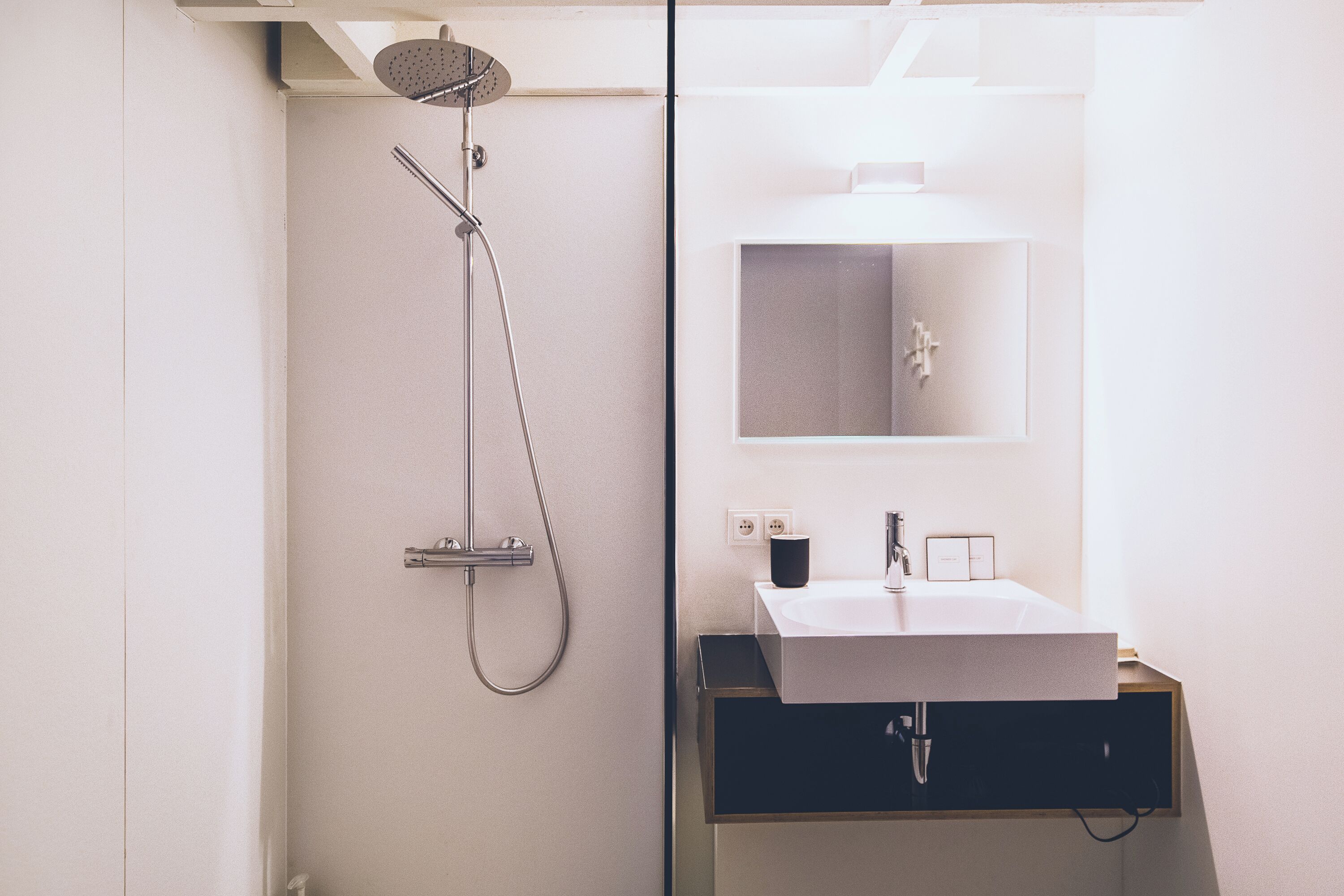 A modern bathroom with a shower, a sink, and a mirror.