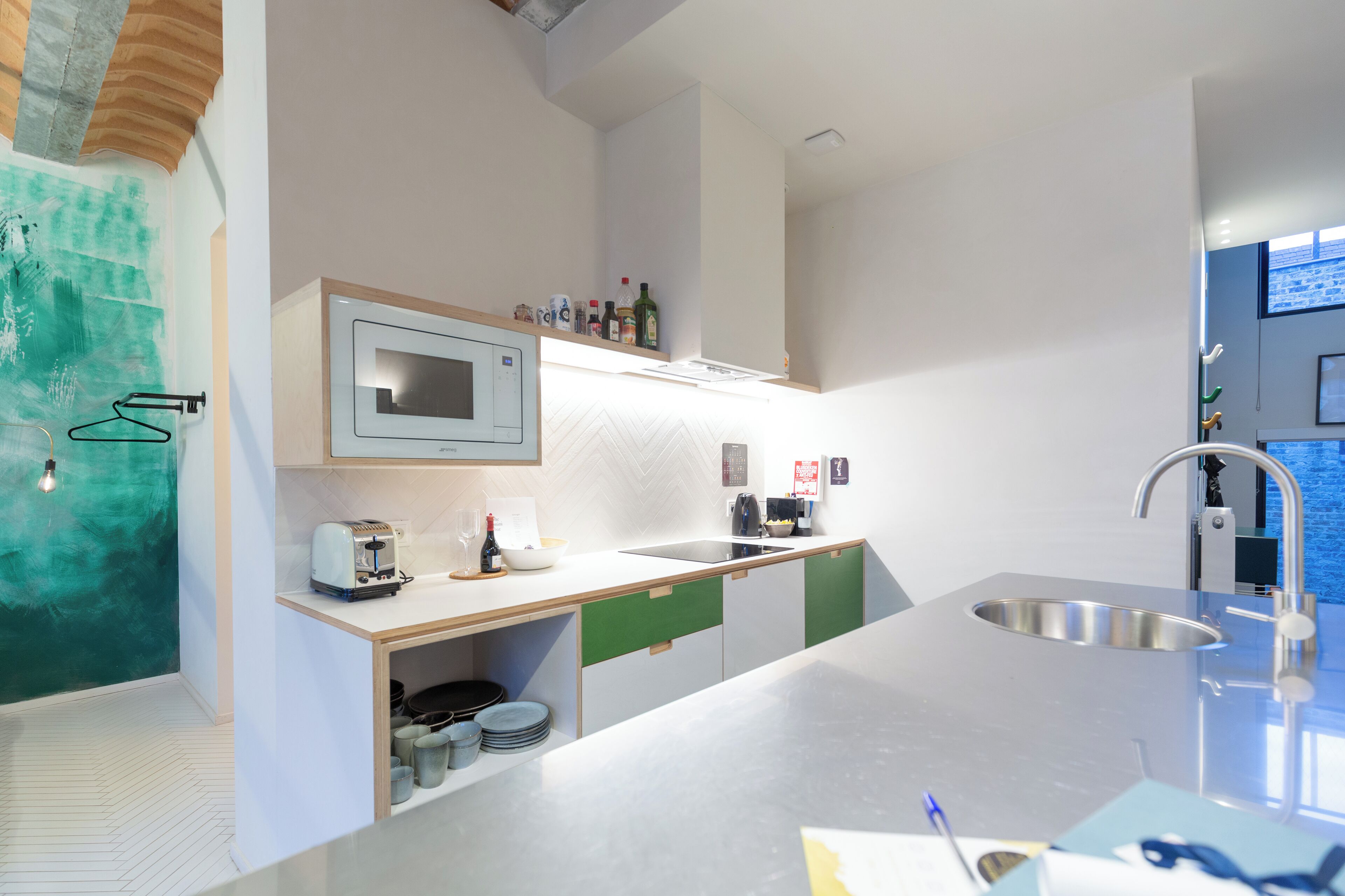 Een moderne keuken met een ingebouwde magnetron, een roestvrijstalen spoelbak en een houten aanrechtblad.