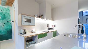 Een moderne keuken met een ingebouwde magnetron, een roestvrijstalen spoelbak en een houten aanrechtblad.