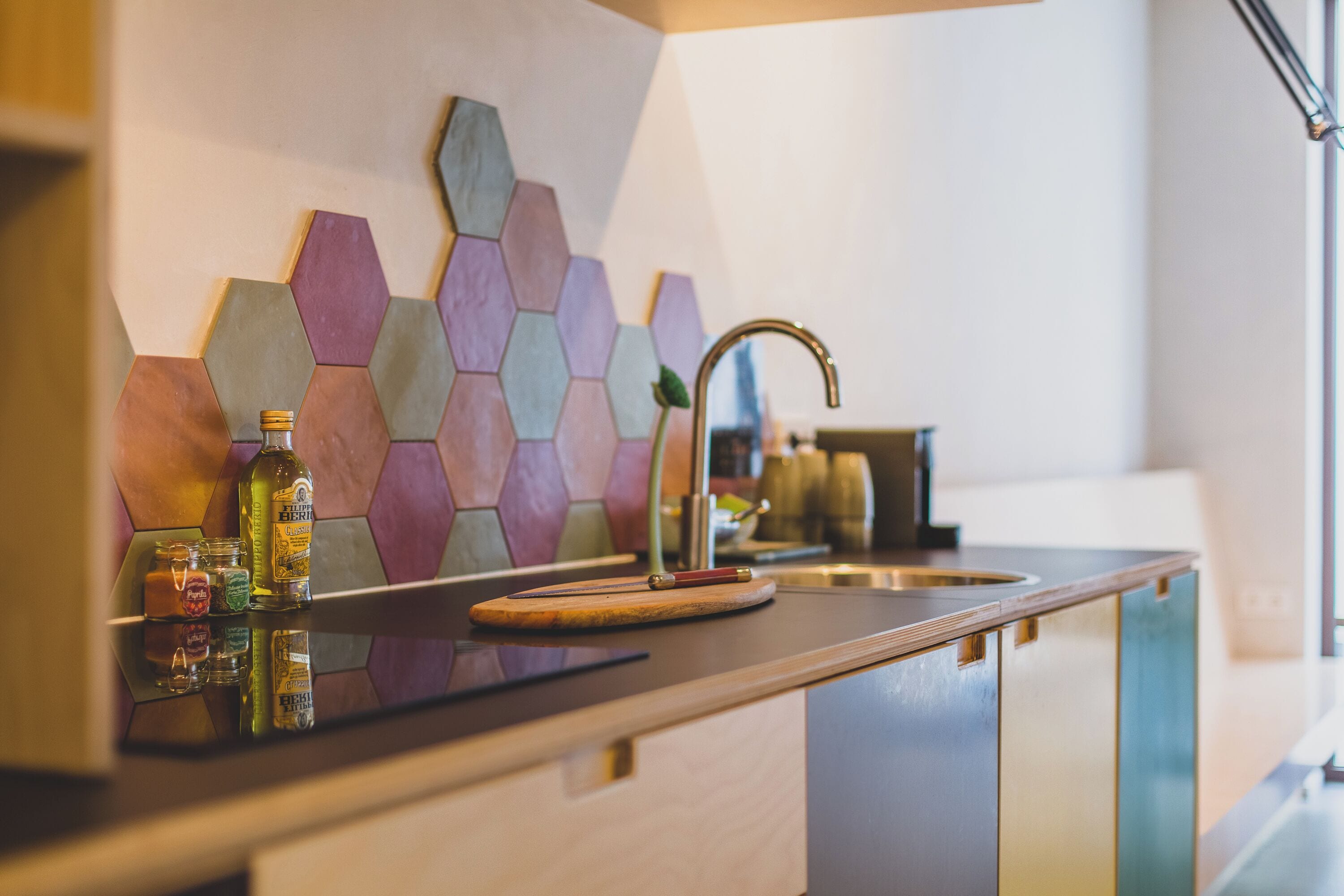 Une cuisine moderne avec un dosseret de crédence en carreaux hexagonaux, un évier en acier inoxydable et un plan de travail en bois.