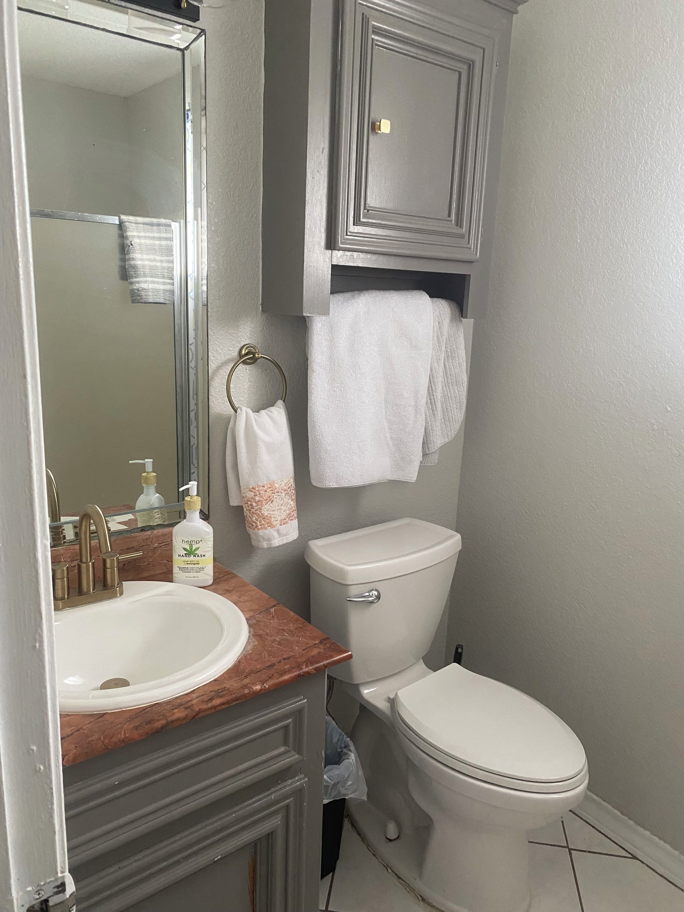 A bathroom with a white sink, a mirror, a toilet, and a towel rack.