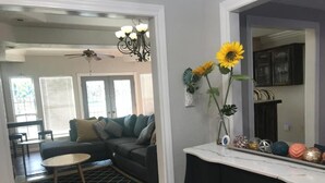 Una sala de estar con un sofá modular, una mesa de centro y un jarrón decorativo con girasoles.