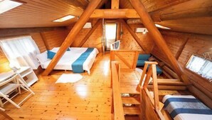 Un intérieur en bois avec un lit en mezzanine, un bureau et une chaise.