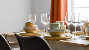 A dining table set with yellow and green bowls, wine glasses, and cutlery. - Charming 5-Bed Victorian House (Worcestershire)