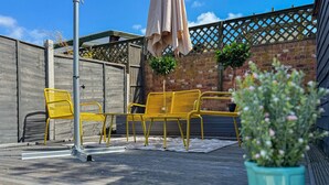A wooden deck with yellow chairs and a potted plant. - Charming 5-Bed Victorian House (Worcestershire)