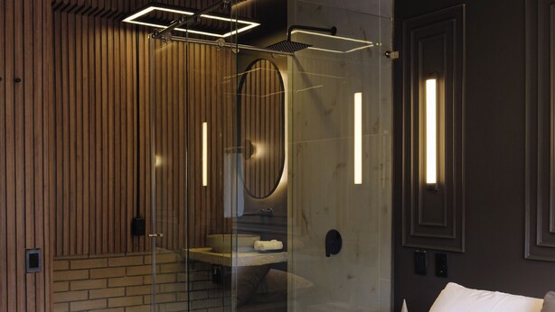 Une chambre moderne avec un grand lit, une cabine de douche en verre et un lambris mural en bois.