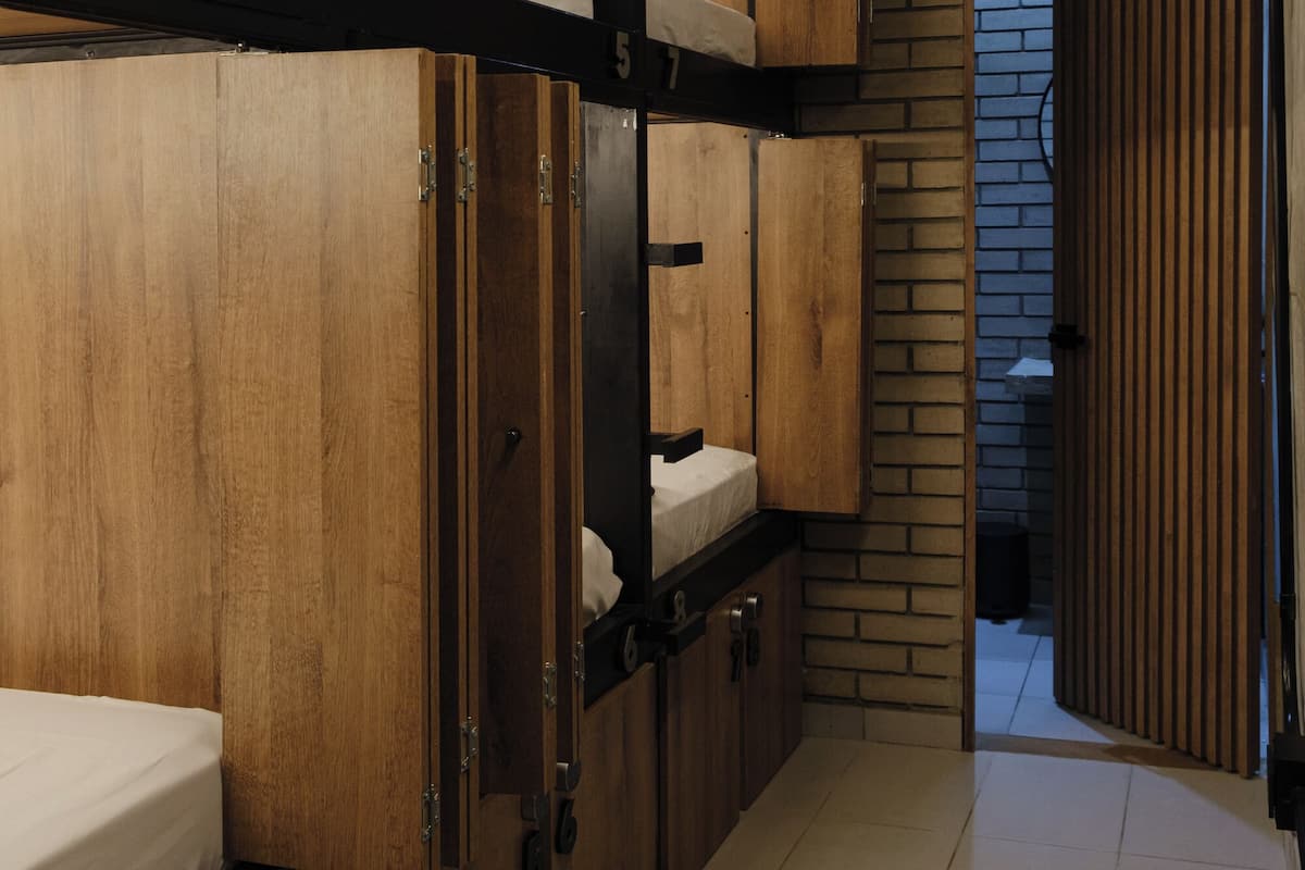 A corridor with bunk beds, wooden walls, and a tiled floor.