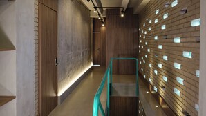 Un intérieur moderne avec un mur en bois, une rambarde en métal et un élément décoratif mural éclairé.