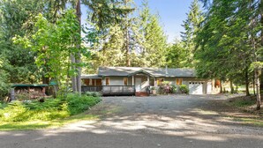 A lodge with a gravel driveway, surrounded by dense forest.