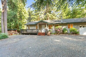 A two-story house with a front porch, a covered deck, and a gravel driveway. - Mt. Baker Cabin | Hot Tub | Fiber Internet | Generator (Deming)