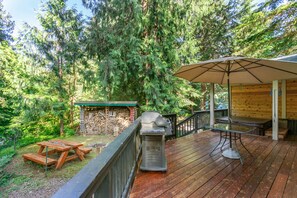 A wooden deck with a barbecue grill, picnic table, and umbrella. - Mt. Baker Cabin | Hot Tub | Fiber Internet | Generator (Deming)
