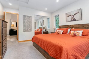 A bedroom with a large bed, a dresser, a mirror, and a deer painting on the wall.