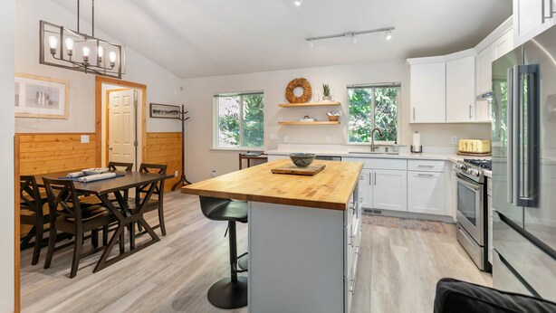 A modern kitchen with white cabinets, a wooden island, and stainless steel appliances.