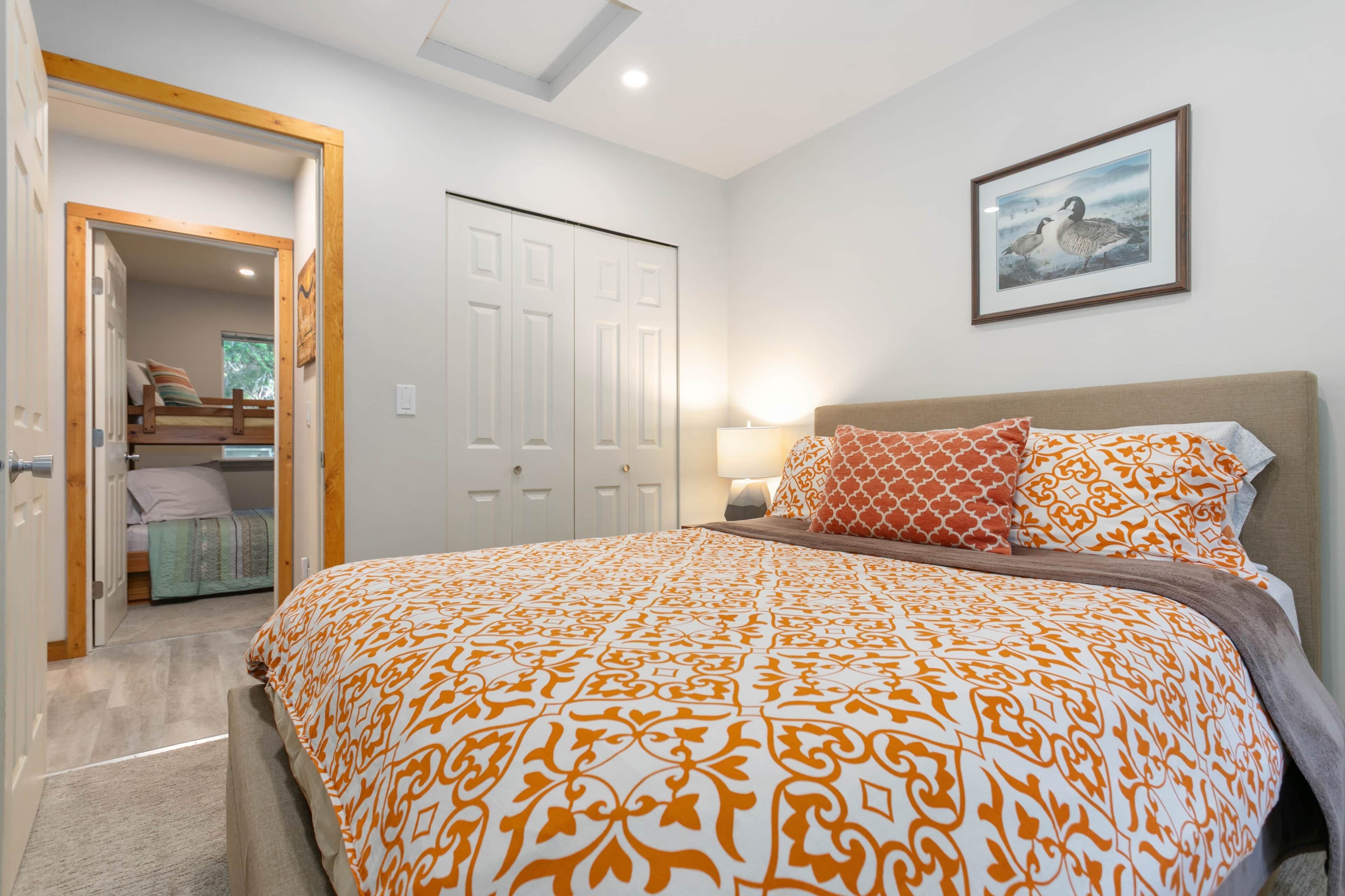 A bedroom with a large bed, a bedside table with a lamp, a wardrobe, and a framed picture on the wall.