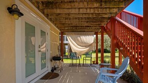 A covered patio with a red railing, a blue chair, and a white canopy.