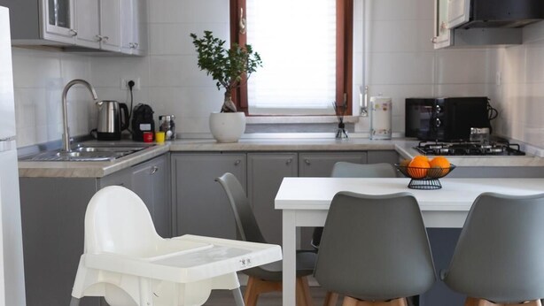 A modern kitchen with grey cabinets, a white dining table, and two grey chairs. - ✨Relax at Lake Garda – Free Wi-Fi, Private Garden (Lombardia)