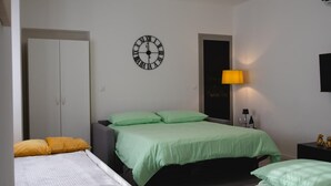 A bedroom with two beds, a wardrobe, a clock, a lamp, and a door. - ✨Relax at Lake Garda – Free Wi-Fi, Private Garden (Lombardia)